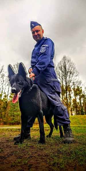 Zdjęcie przedstawia przewodnika psa ze swoim psem służbowym.