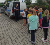 Policjantka pokazuje dzieciom policyjny radiowóz